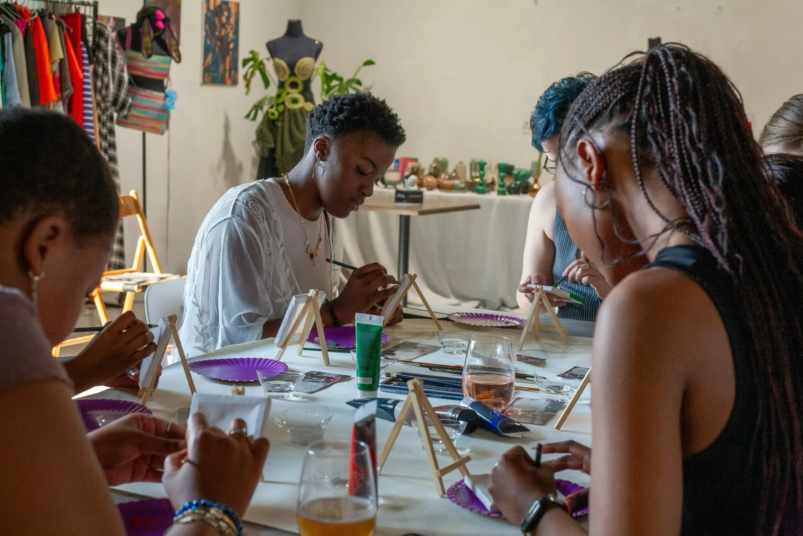 Friends painting small canvases together around a table