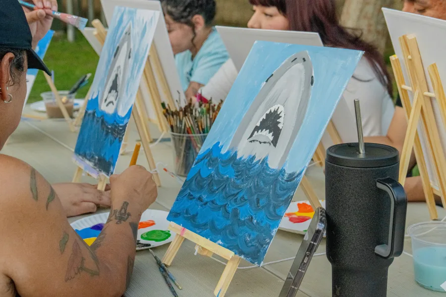 Painters at easels with brushes, palettes and shark paintings on canvas